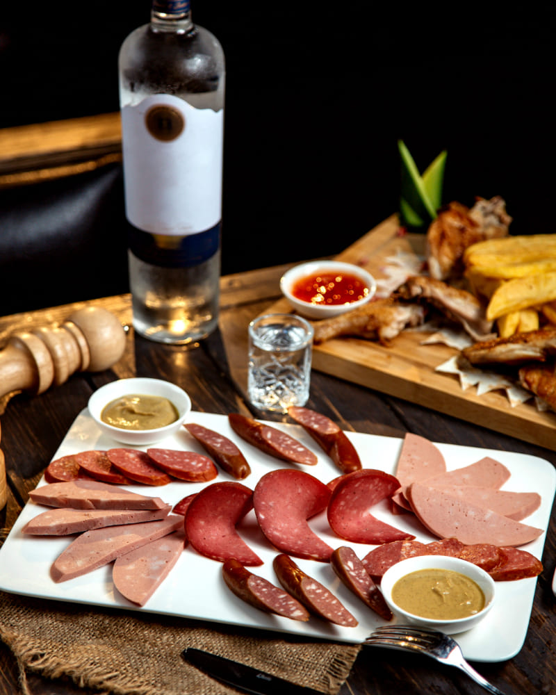 Tabla de embutidos Colombo Alemana con copas de vino y cerveza para maridaje