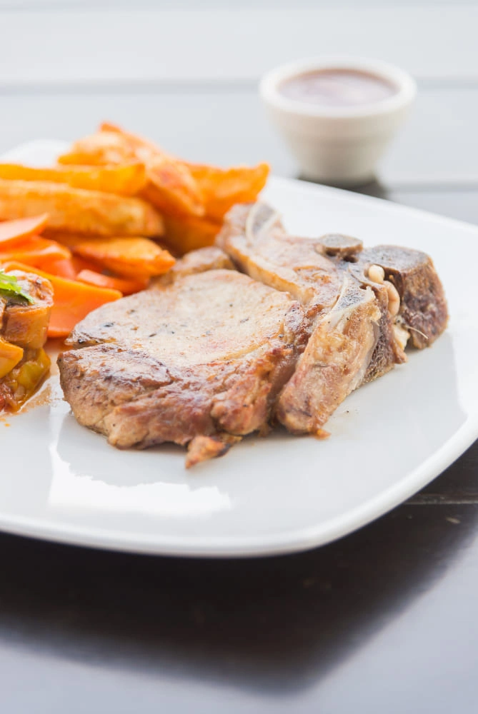 Pernil a la Pimienta Colombo Alemana servido con ensalada fresca y vino tinto