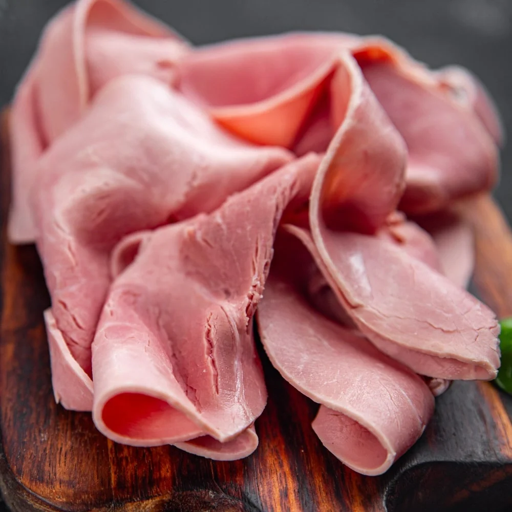 Mortadela Jamonada Colombo Alemana en rodajas sobre tabla de cocina